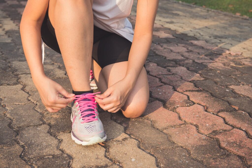 Woman Lacing Up Her Gray and Pink Nike Low-top Athletic Shoe